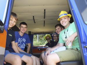 Fünf Jugendliche sitzen in einem Bus und blicken durch die offene Tür.